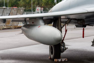 Nuremberg, Almanya - 25 Mayıs 2025: Islak bir yüzey üzerinde gri bir askeri uçağın kanat, iniş takımları ve harici yakıt tankının yakın görüntüsü.