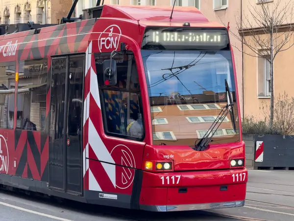 Nuremberg, Almanya, 2025 Şubat 8. Tramvay: Siyah beyaz grafikli kırmızı bir tramvay, ön camlarındaki binaların yansımasını yakalayarak yakın planda gösterilmektedir.