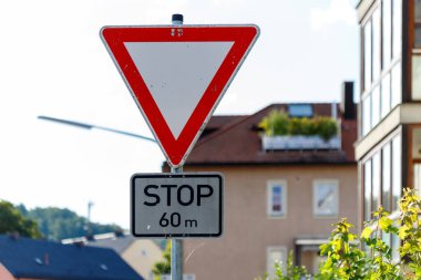 Bulanık bir evin ve binanın önünde, dur işaretinin üzerinde bir Alman verim levhası duruyor. Gökyüzü çoğunlukla berrak ve parlak..