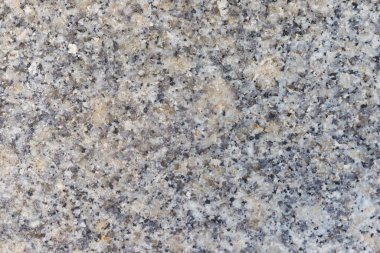 Siyah, gri ve bej mineral tanelerinin yer aldığı benekli granit yüzeyin yakın çekimi.