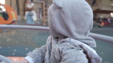 Sıcak giysili küçük bir çocuk atlıkarıncada dönüyor. Yüksek kalite 4k görüntü