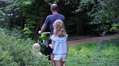 Baba ve çocukları parkta yol boyunca yürüyorlar. Yüksek kalite 4k görüntü