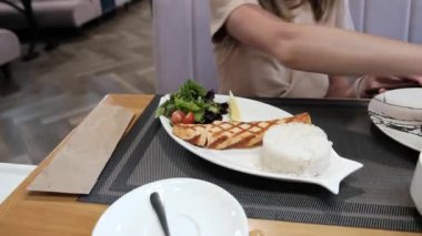 Young woman sitting in a restaurant ordering a dish of fish. High quality 4k footage