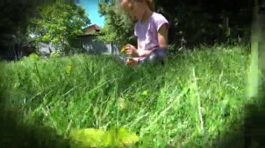Portrait of a little sad girl sits on the lawn under the spruce. High quality 4k footage