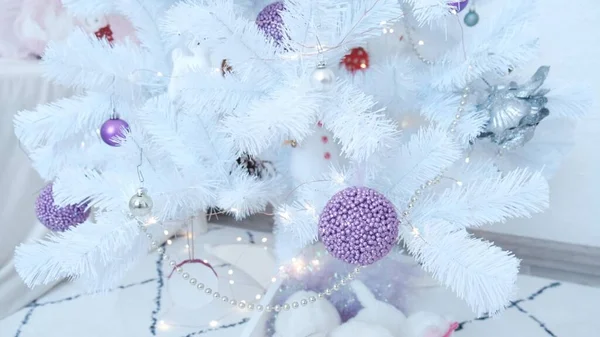 Close-up of a purple Christmas ball hanging on a white Christmas tree. High quality 4k footage