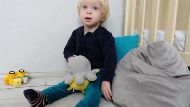 Хлопчик Іграшками Сидить Підлозі Дитячій Кімнаті Вказує Пальцем Високоякісні Кадри — стокове відео