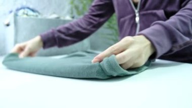 Womens hands fold clothes in a laundry room. High quality 4k footage