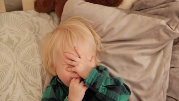 Ein Kleiner Junge Liegt Auf Kissen Und Schlägt Sich Mit — Stockvideo