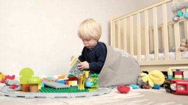 Çocuk odasında yerde oturuyor ve kendine bir ev yapıyor. Yüksek kalite 4k görüntü