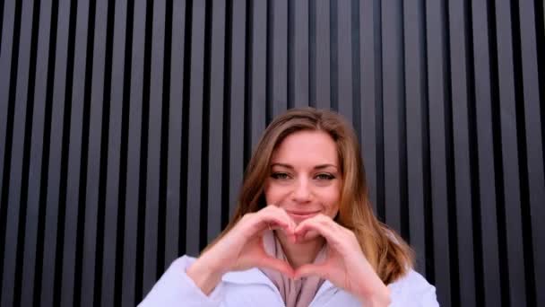 美しい若い女性の笑顔と彼女の手のひらから心を作る 高品質4K映像 — ストック動画