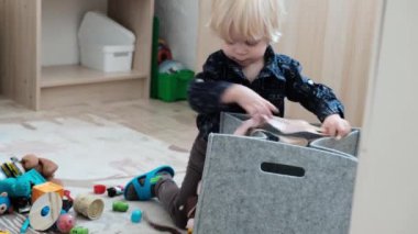 Küçük yakışıklı çocuk oyuncaklarını yere bırakarak sepete koyuyor. Yüksek kalite 4k görüntü