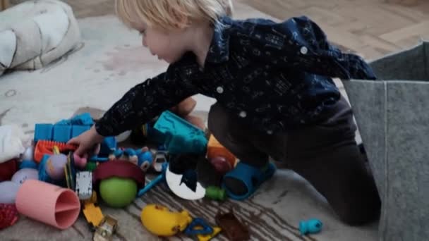 어린아이는 장난감을 치우고 미소를 짓습니다 고품질 — 비디오