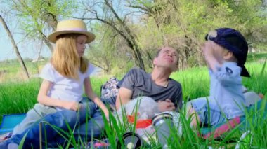  Baba ve kız ve oğul çimlere uzanıp gökyüzüne bakıyorlar. Yüksek kalite 4k görüntü