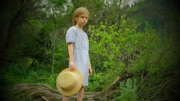 Elinde hasır bir şapka tutan genç bir kızın tam boy fotoğrafı. Yüksek kalite fotoğraf