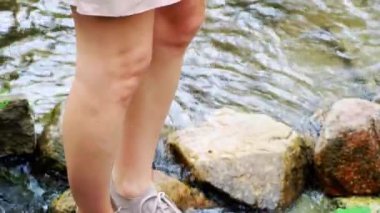 Bir kadının ayağı, nehrin karşısına, kayalıklara doğru bir adım atar. Yüksek kalite 4k görüntü