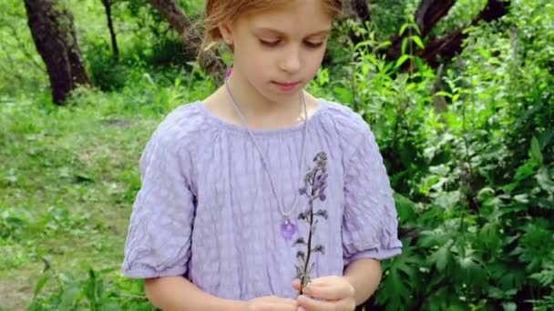 悲しみの少女は森の真ん中で彼女に摘まれた花を見ている 高品質4K映像 — ストック動画