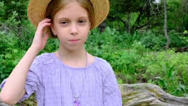 一个戴着草帽的女孩看着摄像机 与绿色的天性格格不入 高质量的4K镜头 — 图库视频影像