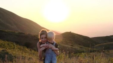 Mutlu aile kavramı. Anne, oğlunun günbatımında fotoğraf çekmesini kameraya gösterir. Yüksek kalite 4k görüntü