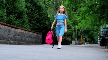 Dokuz yaşında bir kız elinde bir sırt çantasıyla caddede yürüyor. Yüksek kalite 4k görüntü