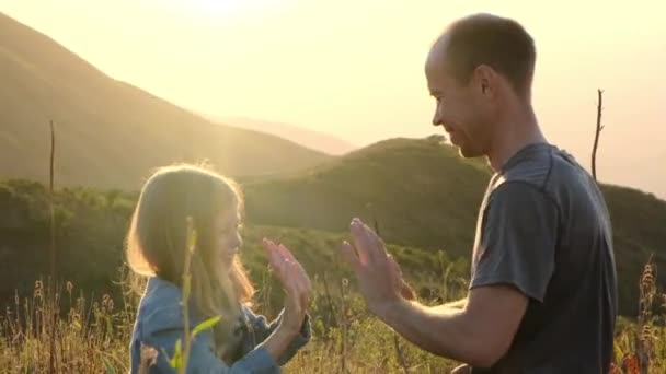 パパは娘とクラップをする 自然の中で幸せな父と娘が夕日を過ごしています 高品質の4K映像 — ストック動画