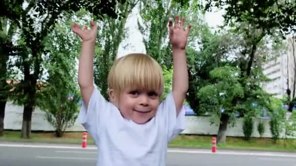 一个小男孩在城市的背景下举起双手 高质量的4K镜头 — 图库视频影像
