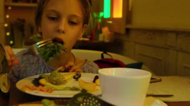 Dokuz yaşında bir kız restoranda salata yiyor. Yüksek kalite 4k görüntü