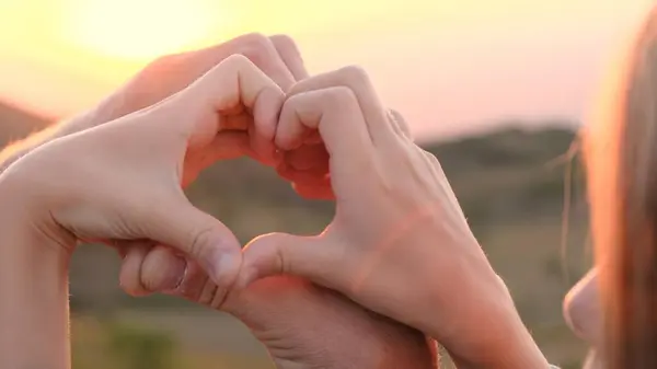  Gün doğumunda aşk kalbi ellerden şekillenir. Gün batımının ışığı ellerinde. Fotoğraf.