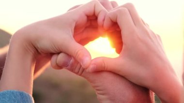  Gün doğumunda aşk kalbi ellerden şekillenir. Gün batımının ışığı ellerinde. Yüksek kalite 4k görüntü