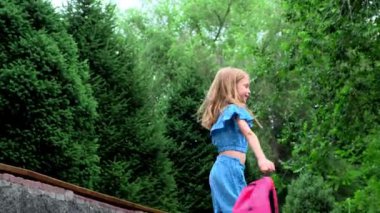 9 yaşında güzel saçlı bir kız çocuğu sırt çantasıyla dönüyor. Yüksek kalite 4k görüntü