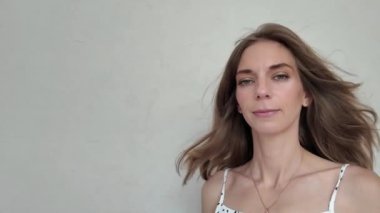 Rüzgarda dalgalanan güzel saçları olan gizemli genç kadın kameraya bakıyor ve gülümsüyor. Yakın plan. Yüksek kalite 4k görüntü