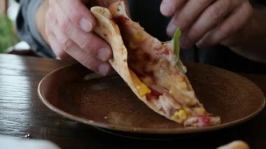 Restoranda bir adam tabaktan bir dilim pizza alır ve bir parça ısırmaya başlar. Yemek reklamları, restoran tanıtımları ve mutfak içeriği için mükemmel bir 4K videosu. Yüksek kalite 4k görüntü