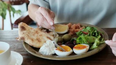 Bir kadının elinin çatalla yakın plan fotoğrafı. Yumurtanın sarısını tabakta nazikçe alıyor. Yemek reklamları, restoran tanıtımları ve mutfak içeriği için mükemmel bir 4K videosu. Yüksek kalite 4k görüntü
