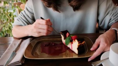 Restoranda bir kadın, güzel, lezzetli süzme peynirli güveci çatal kullanarak çilekle kırıyor. Yüksek kalite 4k görüntü
