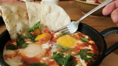 Çok güzel hazırlanmış rafadan yumurtalı bir shakshuka. Kırsal bir tavada lavaşla servis ediliyor. Mükemmel 4K restoran tanıtımları ve mutfak içeriği. Yüksek kalite 4k görüntü