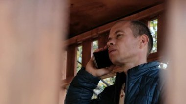 A focused middle-aged man in a jacket has a serious phone conversation outdoors. Perfect 4K video for business, lifestyle, and communication-themed content. High quality 4k footage