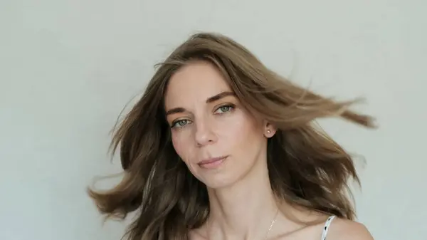 A beautiful young woman with a radiant gaze and loose hair looks intently at the camera. High quality photo