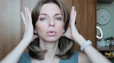 A feminine young woman runs her hand through her hair and looks at the camera. High quality 4k footage