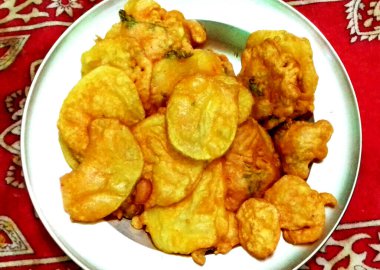 Kırmızı desenli bir kumaşın üzerine yerleştirilmiş, beyaz bir tabakta altın-kahverengi atıştırmalıklar. Abur cuburlar çıtır çıtır ve yeni hazırlanmış görünüyor..