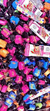 Pembe, mavi ve turuncu tonlarda renkli ambalajlar içeren canlı bir şeker çeşidi bir araya toplanır..