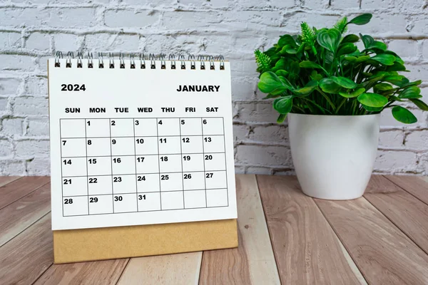 Stock image White January 2024 calendar on office wooden desk with potted plant. 2024 New Year Concept