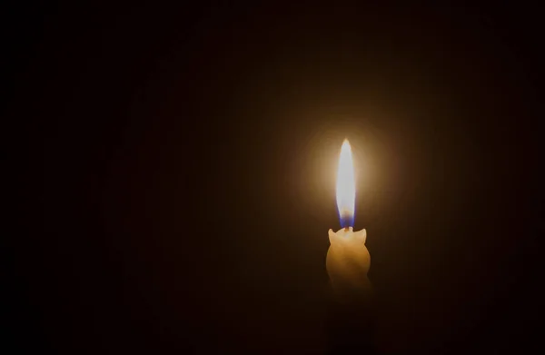 単一の燃焼ろうそくの炎や光は クリスマス 葬儀や記念サービスのための教会でテーブルの上に黒または暗い背景にスパイラルホワイトキャンドルに輝いています — ストック写真