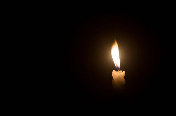 葬礼或追悼会上 在教堂桌上的黑色或深色背景上 一根燃烧着的蜡烛在螺旋形的白色蜡烛上闪烁着 以抵御微风吹拂 — 图库照片