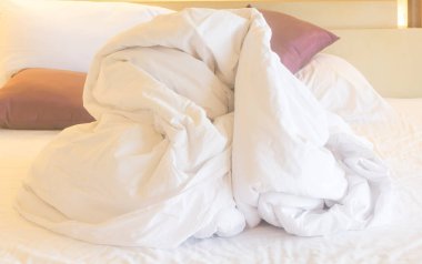 Beyaz battaniye ve otel odasındaki diğer yatak örtüleri misafirlerin gece boyunca kullanmasından sonra dağınık bırakılır..