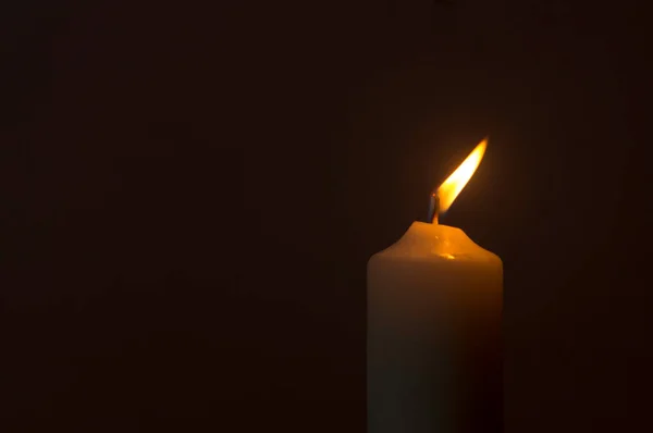 圣诞节 葬礼或追悼会上 在教堂桌子上黑色或深色背景的白色蜡烛上闪烁着模糊的单个燃烧的蜡烛 火焰或灯光 — 图库照片