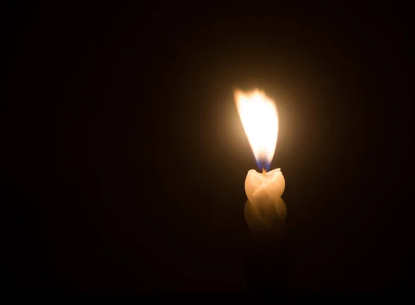 単一の燃焼ろうそくの炎や光は クリスマス 葬儀や記念サービスのための教会のテーブルの上に黒や暗い背景に小さな吹風に対する螺旋状の白いろうそくに輝いている — ストック写真