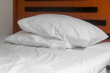 White untidy bed sheet and two pillows set on bed were taken after guest' s use in resort or hotel room.