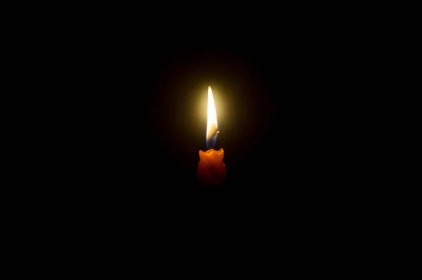 単一の燃焼キャンドル炎や光は コピースペースとクリスマス 葬儀や記念サービスのための教会でテーブルの上に黒または暗い背景にスパイラルオレンジキャンドルに輝いている — ストック写真