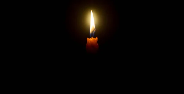 単一の燃焼キャンドル炎や光は コピースペースとクリスマス 葬儀や記念サービスのための教会でテーブルの上に黒または暗い背景にオレンジ色のキャンドルに輝いている — ストック写真