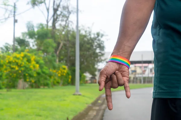 Hand wearing rainbow or lgbtq+ symbol wristband is stretching down with  love symbol to campaign for protection and support on gender diversity or lgbtq+ people and community.