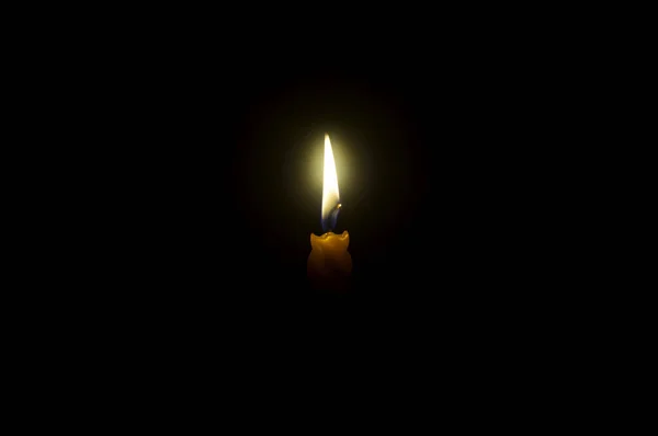 単一の燃焼キャンドル炎や光は コピースペースとクリスマス 葬儀や記念サービスのための教会でテーブルの上に黒または暗い背景に輝くスパイラルオレンジキャンドルです — ストック写真